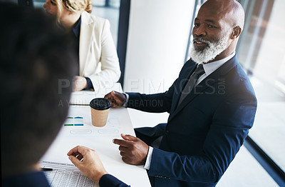 Buy stock photo Shot of a mature businessman having a meeting with his colleagues in an office