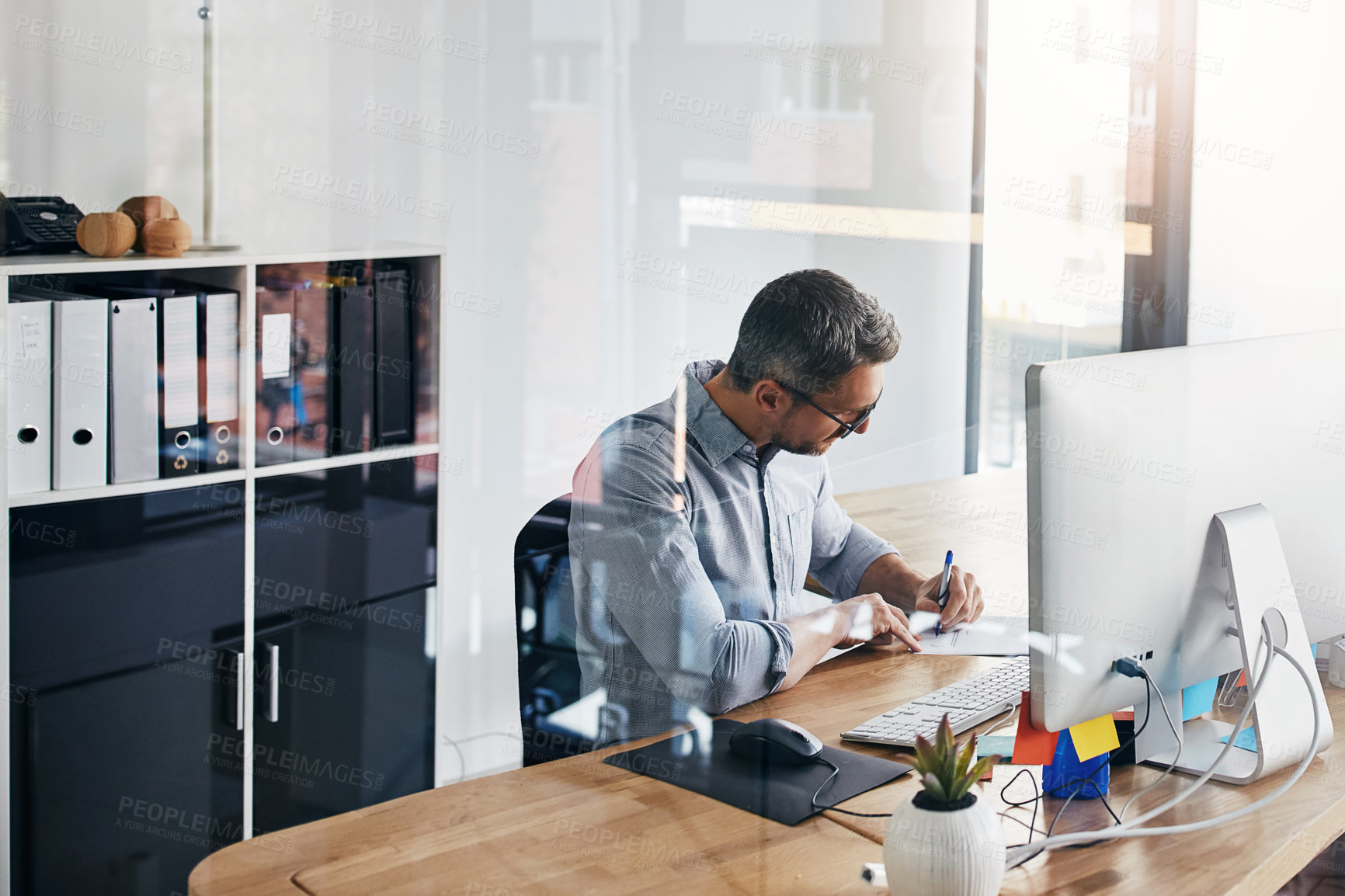 Buy stock photo Cropped shot of a businessman working on his computer at his desk