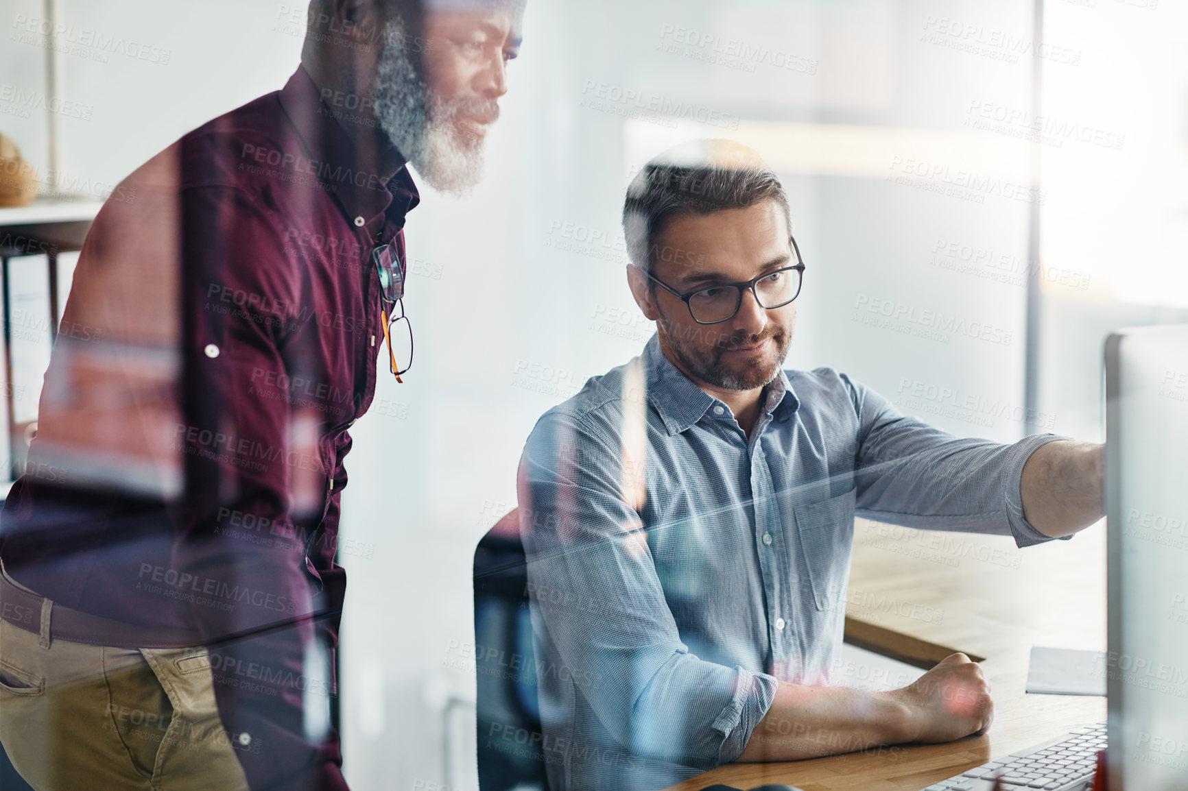 Buy stock photo Shot of two businesspeople working on a computer in an office