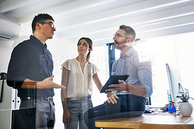 Buy stock photo Shot of a group of businesspeople using a digital tablet in an office