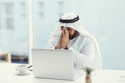 Buy stock photo Cropped shot of a young businessman dressed in Islamic traditional clothing praying while working in his office
