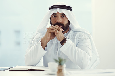 Buy stock photo Cropped portrait of a young businessman dressed in Islamic traditional clothing sitting in his office