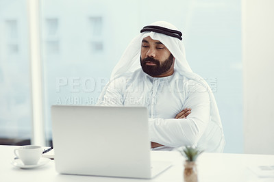 Buy stock photo Cropped shot of a young businessman dressed in Islamic traditional clothing sitting with his arms folded in the office