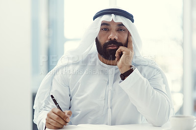Buy stock photo Cropped portrait of a young businessman dressed in Islamic traditional clothing working in his office