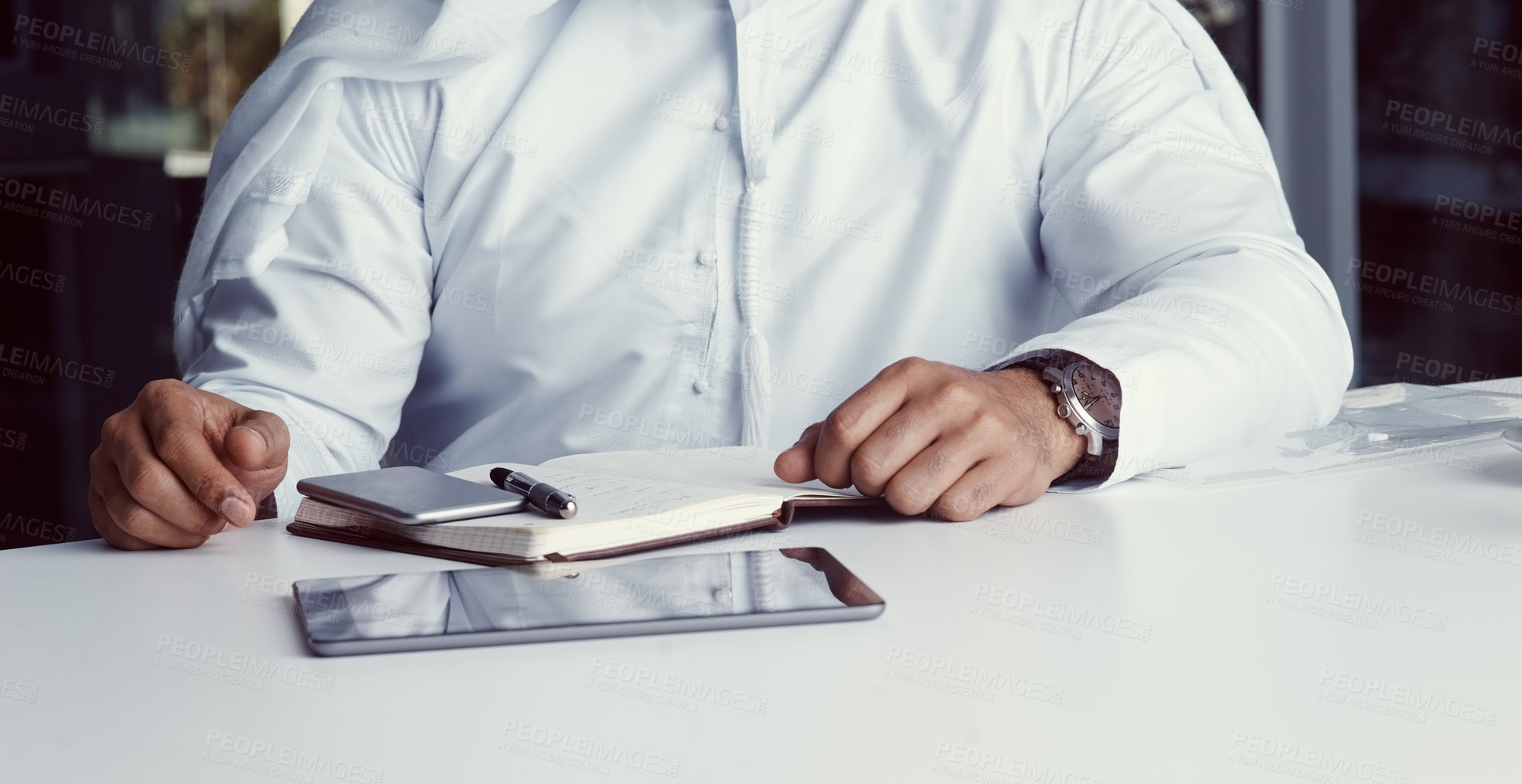 Buy stock photo Cropped shot of an unrecognizable businessman dressed in Islamic traditional clothing working in his office