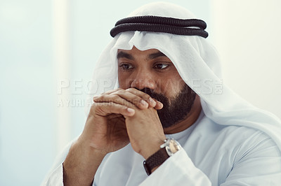 Buy stock photo Cropped shot of a young businessman dressed in Islamic traditional clothing looking thoughtful while working in his office