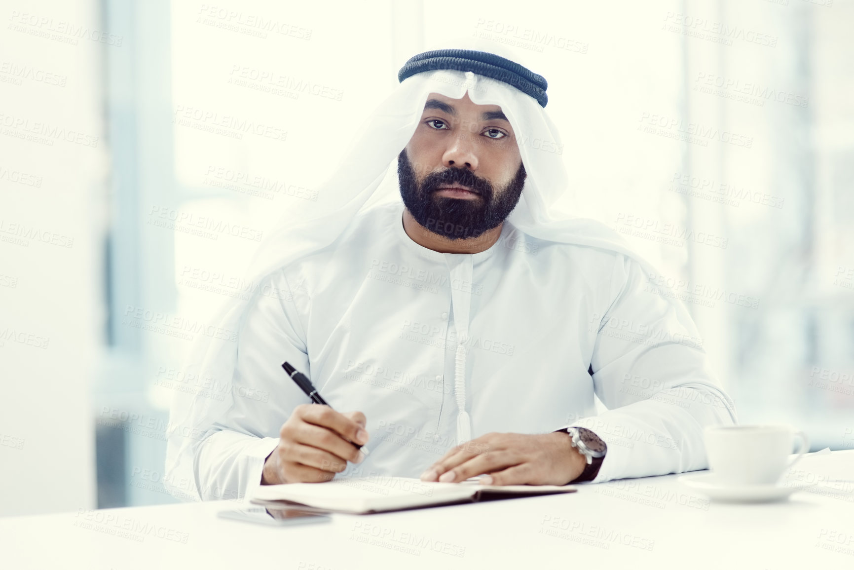 Buy stock photo Cropped portrait of a young businessman dressed in Islamic traditional clothing working in his office