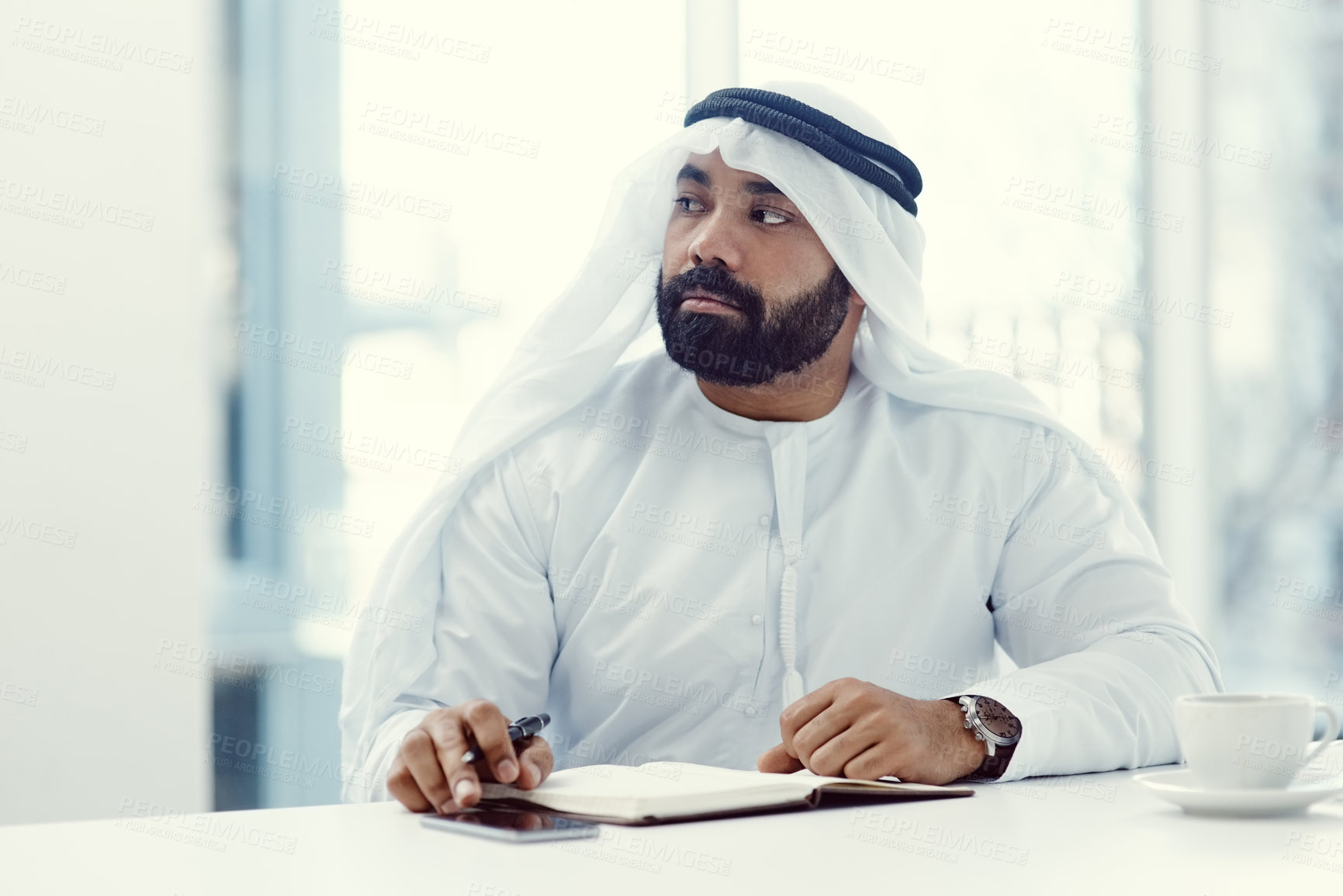 Buy stock photo Cropped shot of a young businessman dressed in Islamic traditional clothing looking thoughtful while working in his office