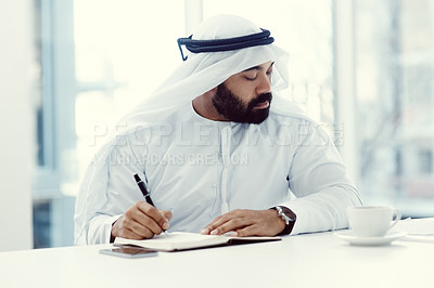 Buy stock photo Cropped shot of a young businessman dressed in Islamic traditional clothing working in his office
