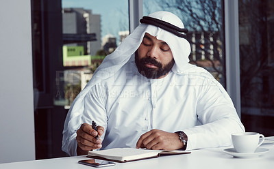 Buy stock photo Cropped shot of a young businessman dressed in Islamic traditional clothing working in his office