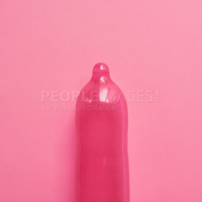 Buy stock photo Studio shot of a pink condom placed against a pink background