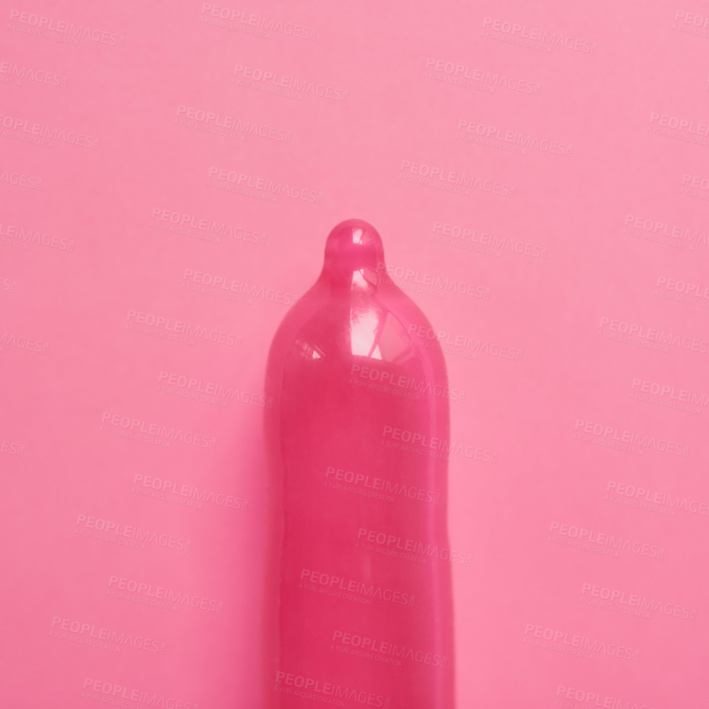 Buy stock photo Studio shot of a pink condom placed against a pink background