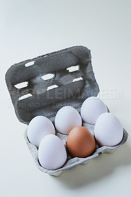 Buy stock photo Studio shot of a box against a grey background containing half a dozen eggs with one egg being different from the rest