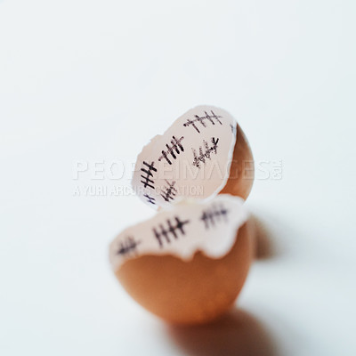Buy stock photo Studio shot of two pieces of broken egg shell against a white background with tally marks inside of it