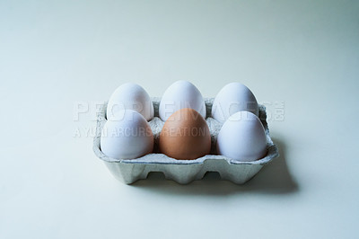 Buy stock photo Studio shot of a box against a grey background containing half a dozen eggs with one egg being different from the rest