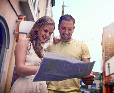 Buy stock photo Shot of a happy young couple reading a map while exploring a foreign city together