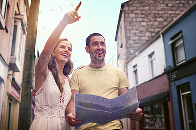 Buy stock photo Shot of a happy young couple reading a map while exploring a foreign city together