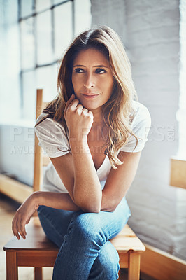 Buy stock photo Shot of an attractive and thoughtful young woman relaxing at home