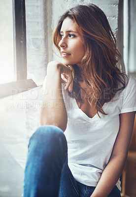 Buy stock photo Shot of an attractive and thoughtful young woman relaxing at home