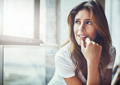 Buy stock photo Shot of an attractive and thoughtful young woman relaxing at home