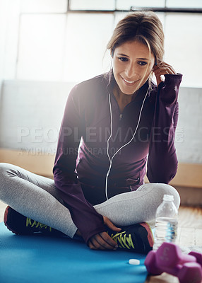 Buy stock photo Shot of an attractive young woman listening to music while working out at home