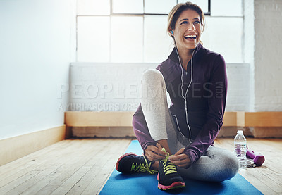 Buy stock photo Shot of an attractive young woman tying her shoelaces while working out at home
