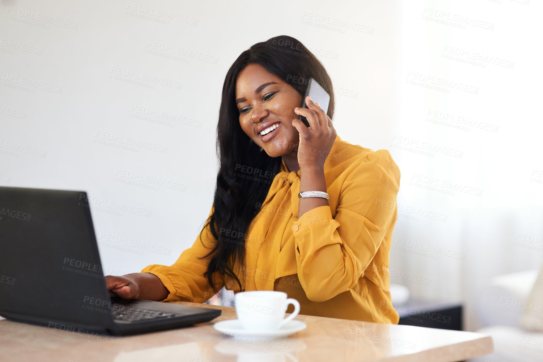 Buy stock photo Shot of a cheerful young businesswoman talking on her cellphone while working on a laptop at home