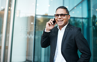 Buy stock photo Cropped shot of a handsome mature businessman making a phonecall with his office in the background