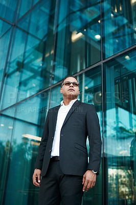 Buy stock photo Low angle shot of a handsome mature businessman standing on the street with his office in the background