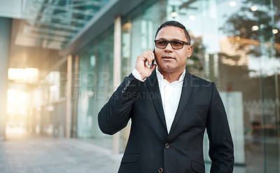 Buy stock photo Cropped shot of a handsome mature businessman making a phonecall with his office in the background