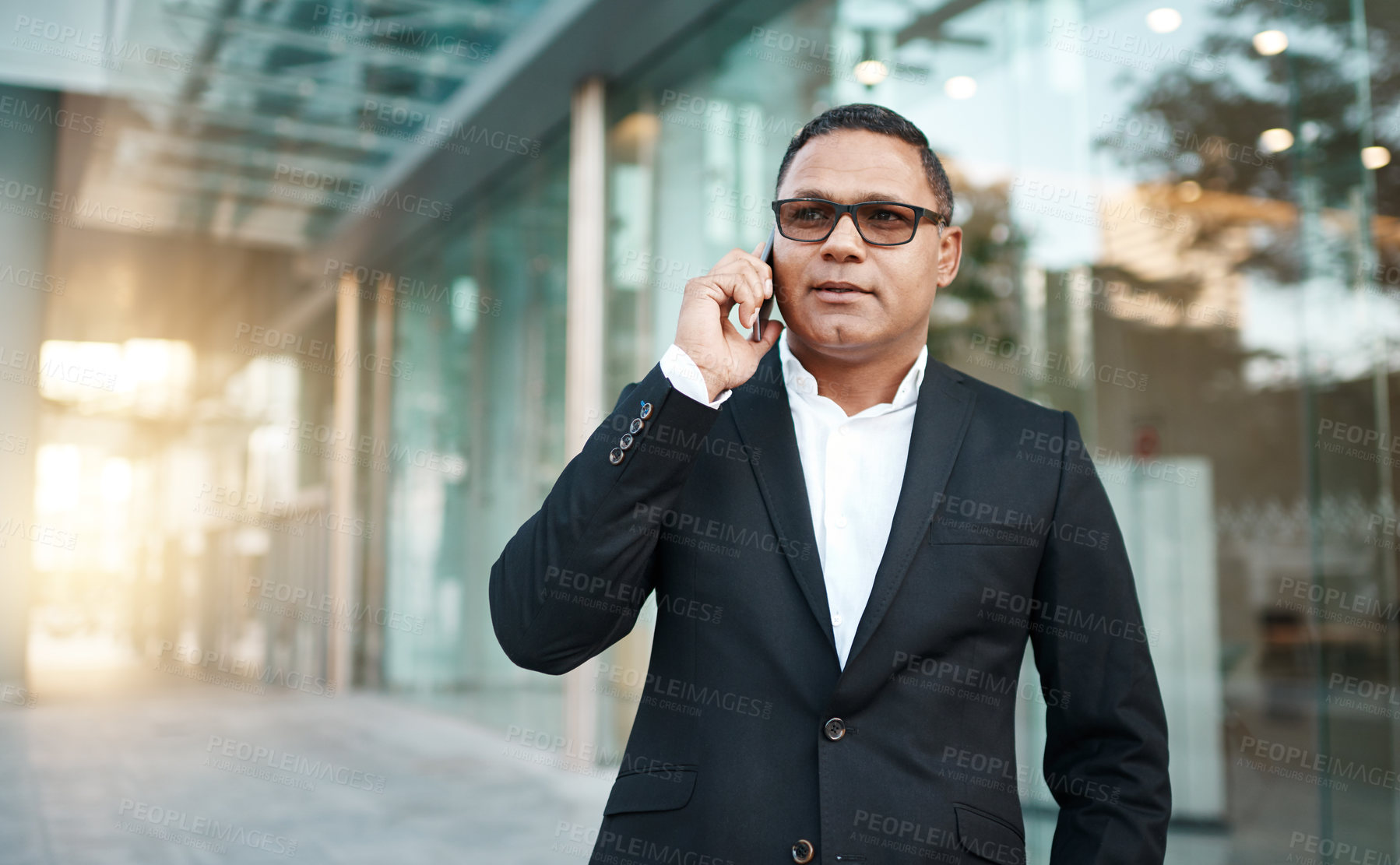 Buy stock photo Cropped shot of a handsome mature businessman making a phonecall with his office in the background