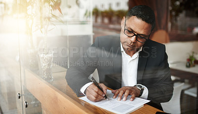 Buy stock photo High angle shot of a handsome mature businessman doing some work while sitting in a coffee shop