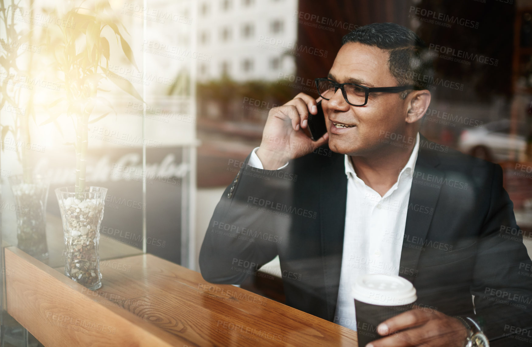 Buy stock photo High angle shot of a handsome mature businessman making a phonecall message while sitting in a coffee shop