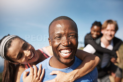 Buy stock photo Shot of a man piggybacking his girlfriend with people standing in the background