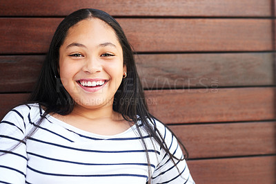 Buy stock photo Portrait of a happy and confident young girl posing against a wooden background