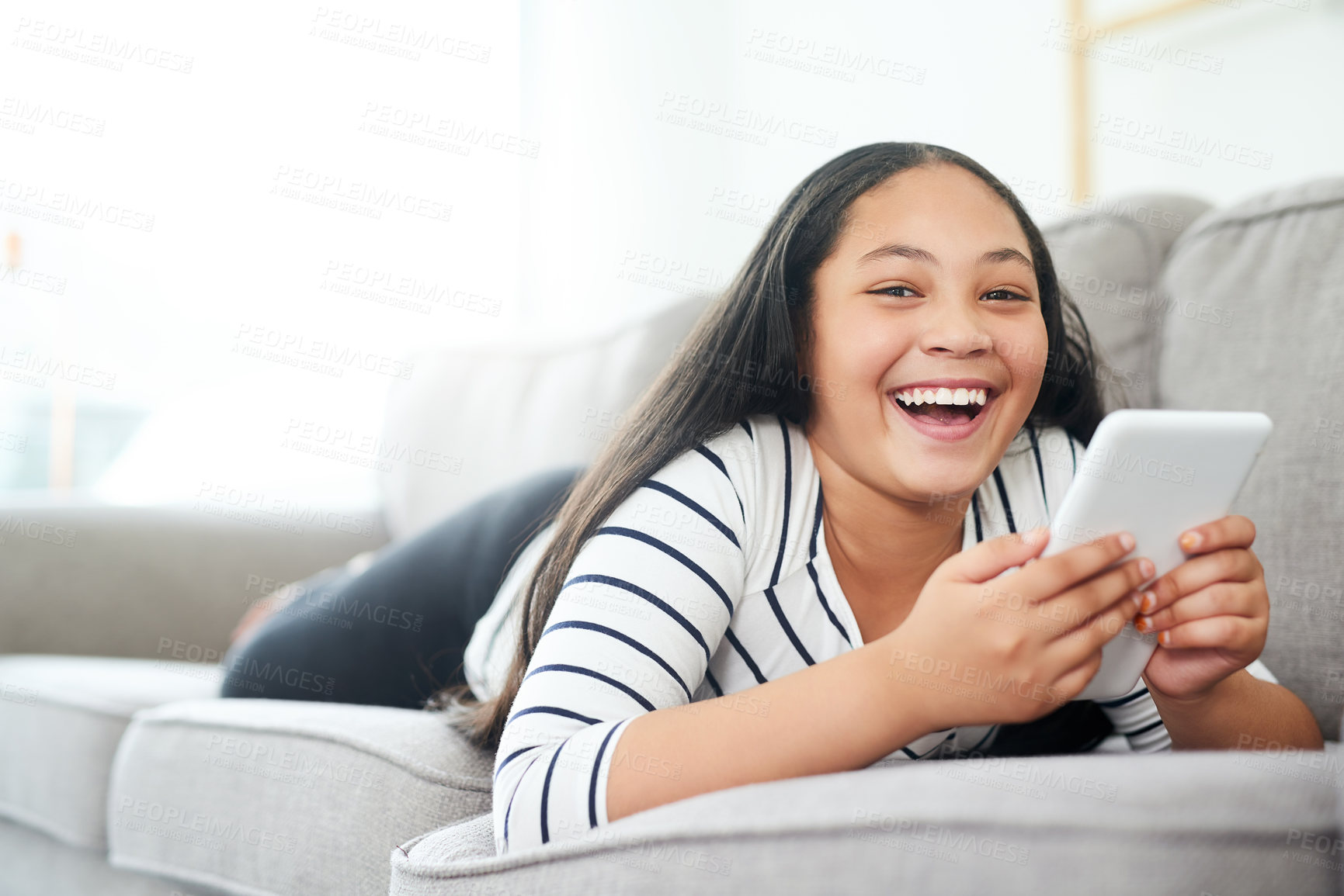 Buy stock photo Portrait of a happy young girl relaxing on the sofa and using a digital tablet