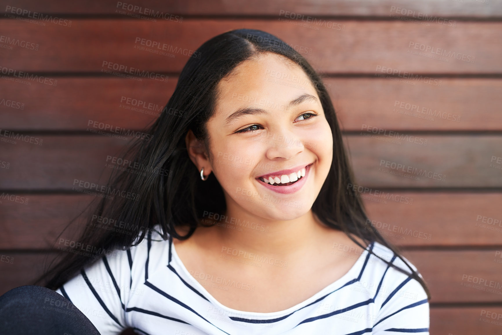 Buy stock photo Shot of a happy young girl posing against a wooden background