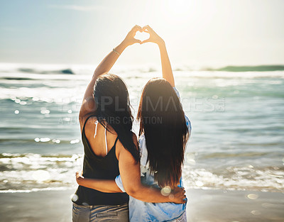 Buy stock photo Rearview shot of two friends forming a heart shape together on the beach