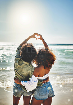 Buy stock photo Rearview shot of two friends forming a heart shape together on the beach