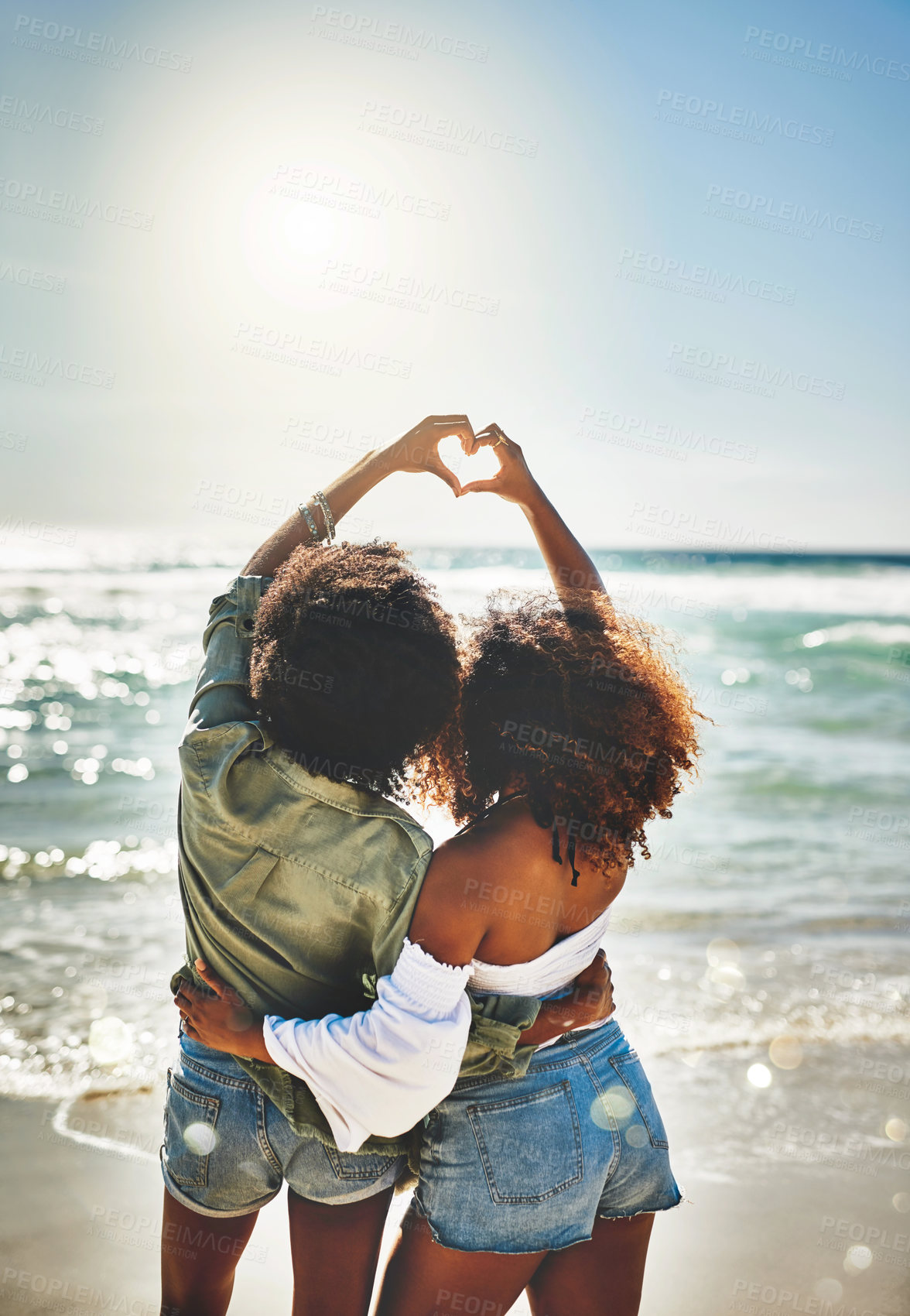 Buy stock photo Rearview shot of two friends forming a heart shape together on the beach