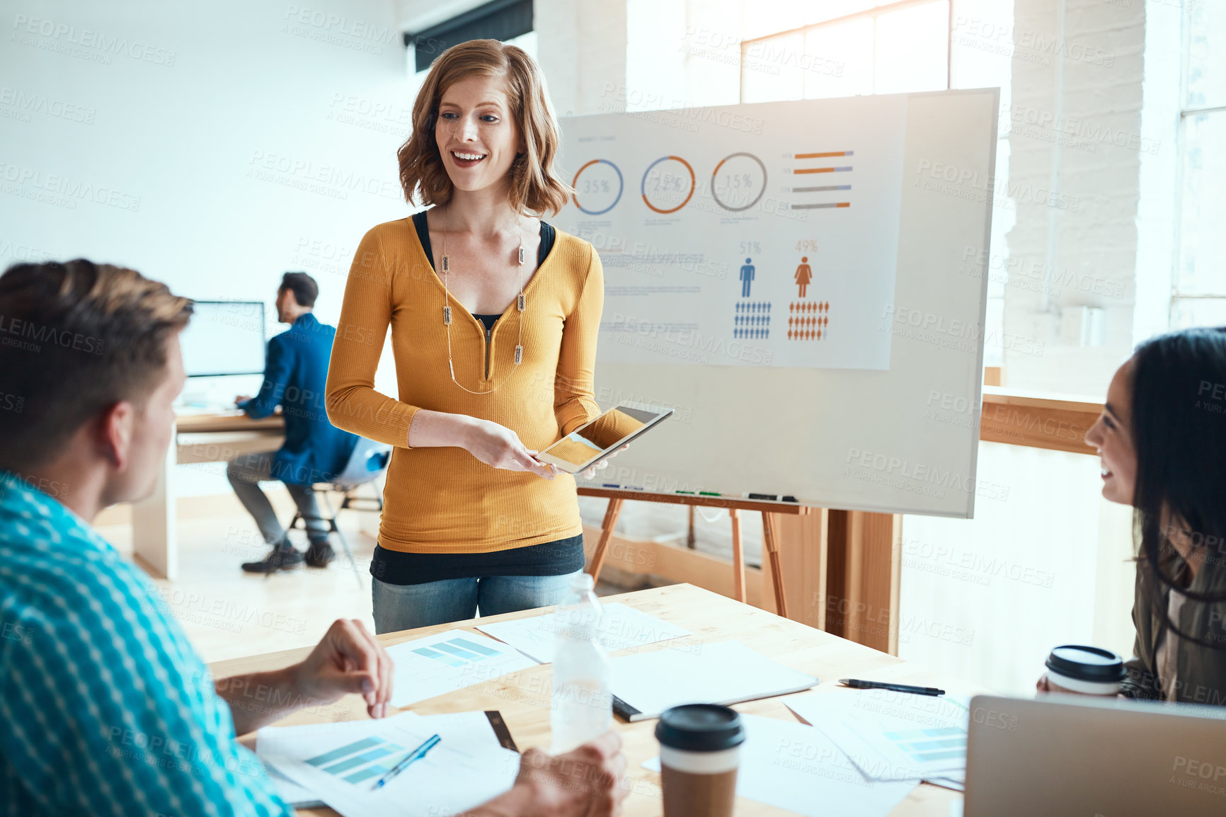 Buy stock photo Shot of a young businesswoman using a digital during a meeting with her colleagues in a modern office