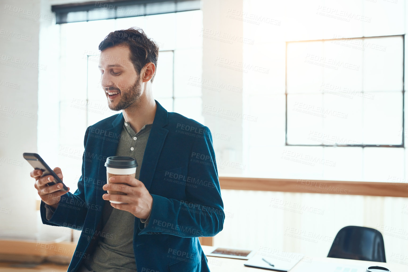 Buy stock photo Cropped shot of a handsome young businessman using his cellphone while working in a modern office