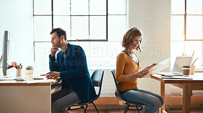 Buy stock photo Cropped shot of two young businesspeople working back to back in a modern office