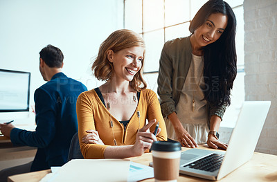 Buy stock photo Shot of two young businesswomen working together in their modern office with a male colleague in the background