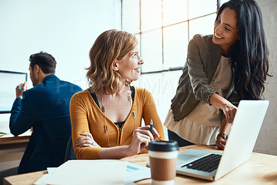 Buy stock photo Shot of two young businesswomen working together in their modern office with a male colleague in the background