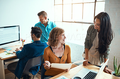 Buy stock photo Shot of two young businesswoman working together in their modern office with two male colleagues in the background