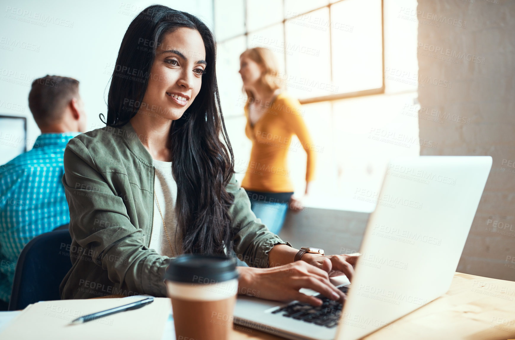 Buy stock photo Cropped shot of an attractive young businesswoman working in a modern office with her colleagues in the background