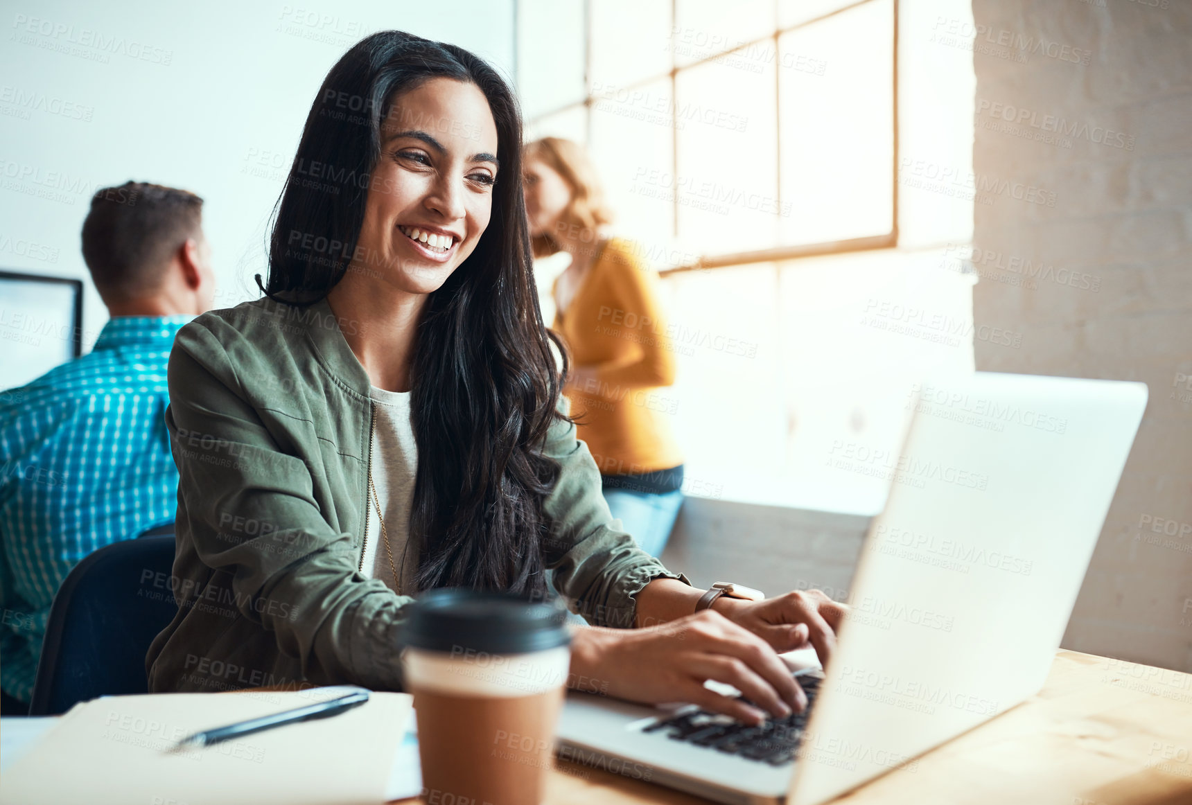 Buy stock photo Cropped shot of an attractive young businesswoman working in a modern office with her colleagues in the background