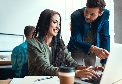 Buy stock photo Shot of two young business colleagues working together in their modern office with a male colleague in the background