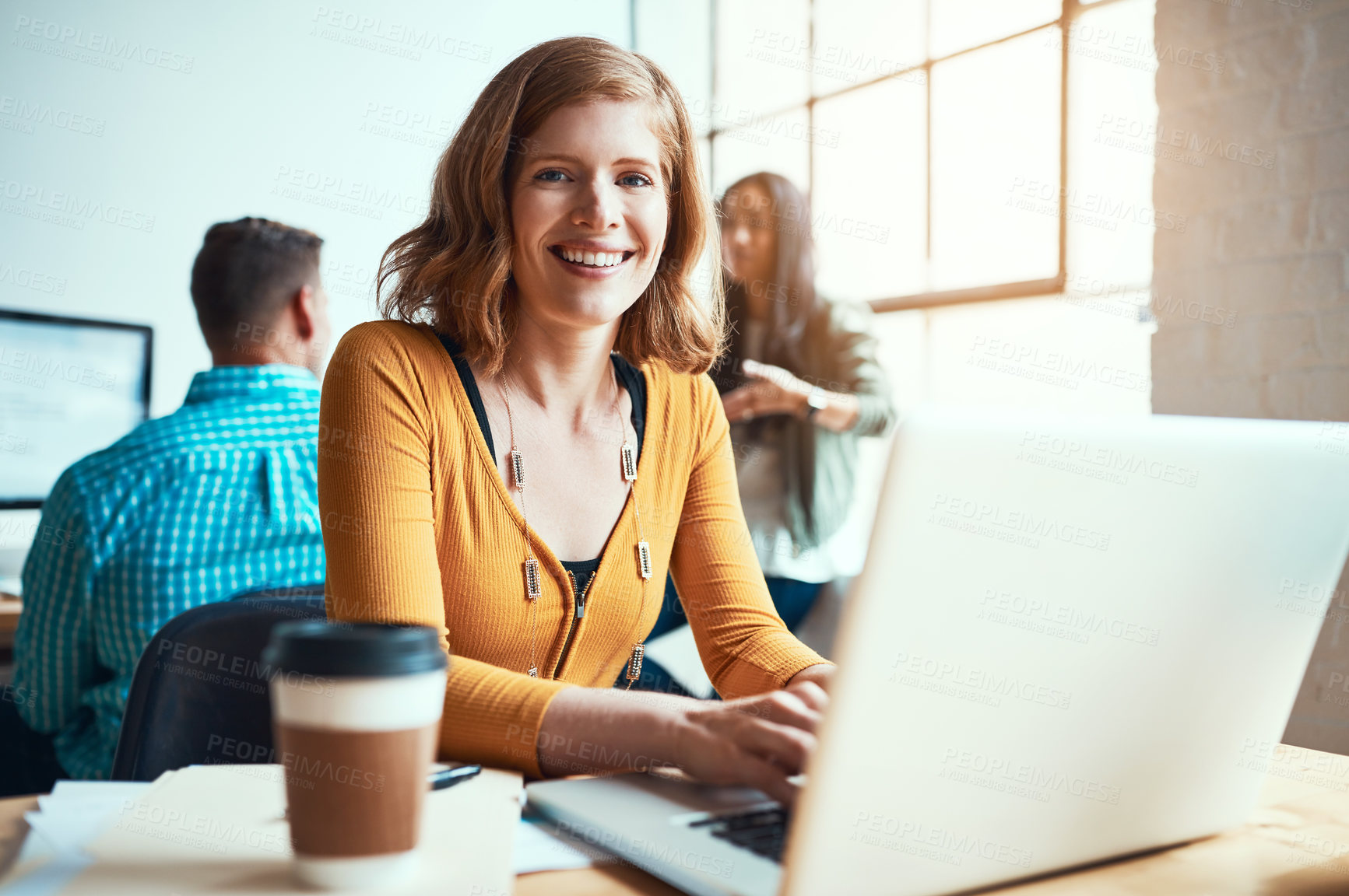 Buy stock photo Cropped portrait of an attractive young businesswoman working in a modern office with her colleagues in the background